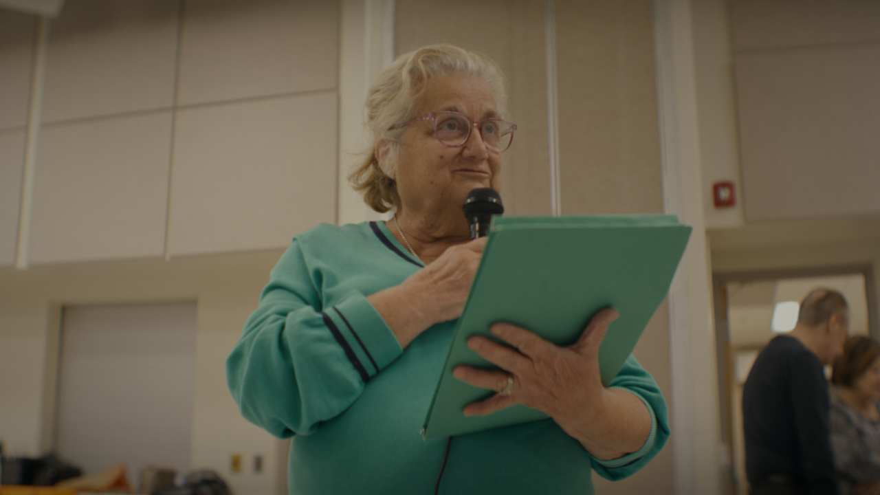 a woman with glasses speaking into a microphone